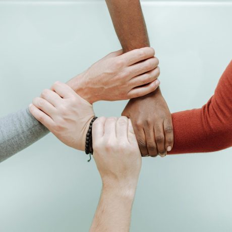 Four people holding each other's wrists in a supportive manner.