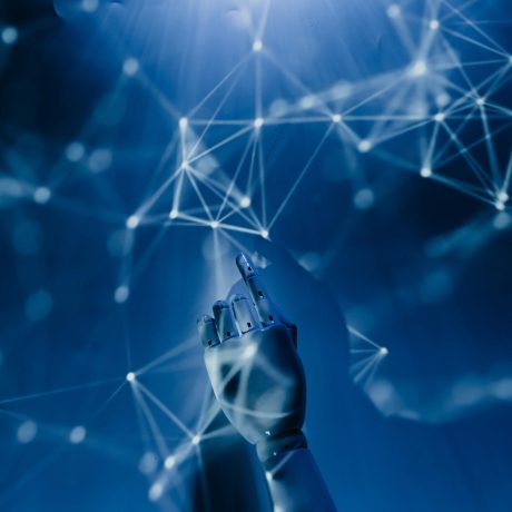 Robotic hand extends it's index finger towards geometric shapes in mid-air. This symbols the connection of artificial intelligence with data.