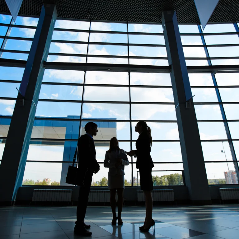 Three business associates having a conversation inside a building.